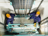 machinists adjusting lift in elevator hoistway