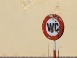 Grunge toilet sign next to old building wall