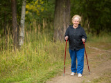 An elderly woman practicing Nordic walking outside of town.