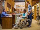Side view of a male student in wheelchair at the counter in college library